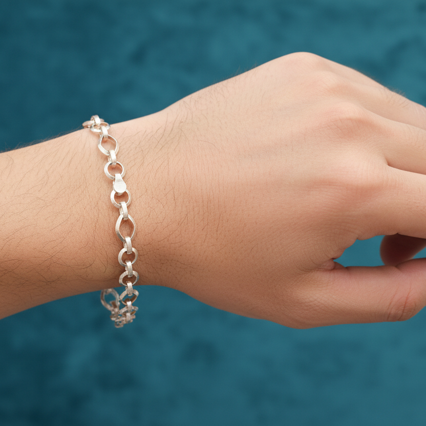 Hand wearing a silver chain bracelet against a blue background