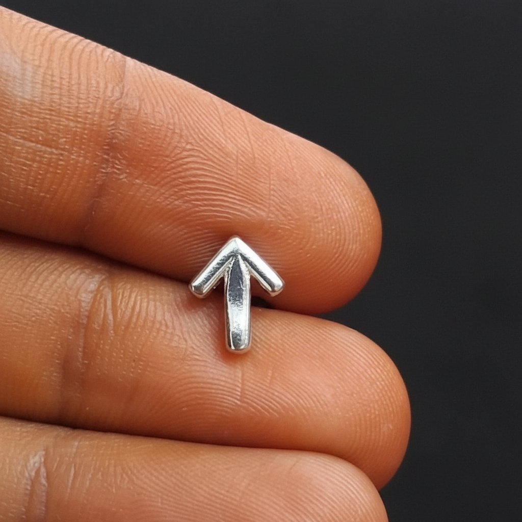 Silver ring with an arrow design on a finger against a red fabric background