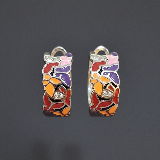Colorful patterned rings on a finger with a black hexagonal object in the background