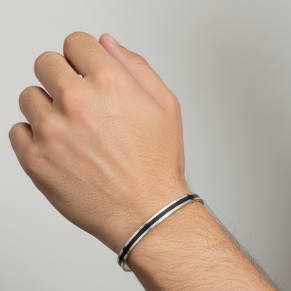 Hand wearing a silver bracelet on a plain background