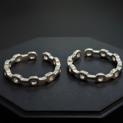 Gold hoop earrings on a black stand with a pink background