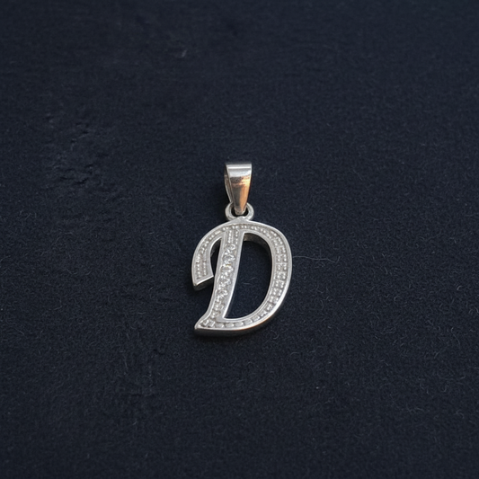 Silver pendant with ruler for scale on a red background
