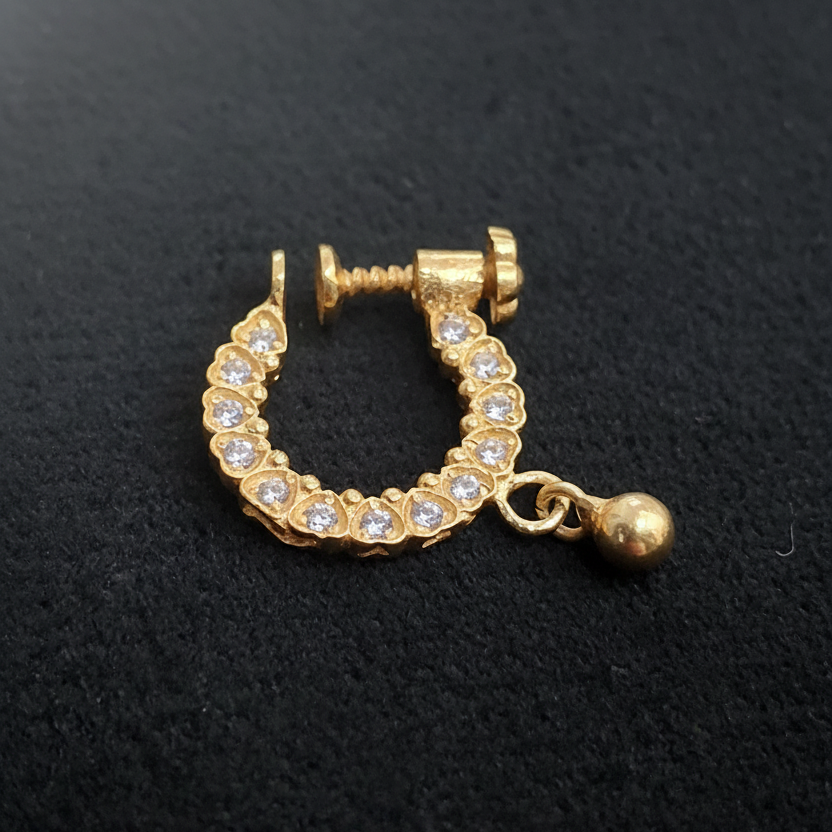 Gold earring with gemstones on a blue textured background