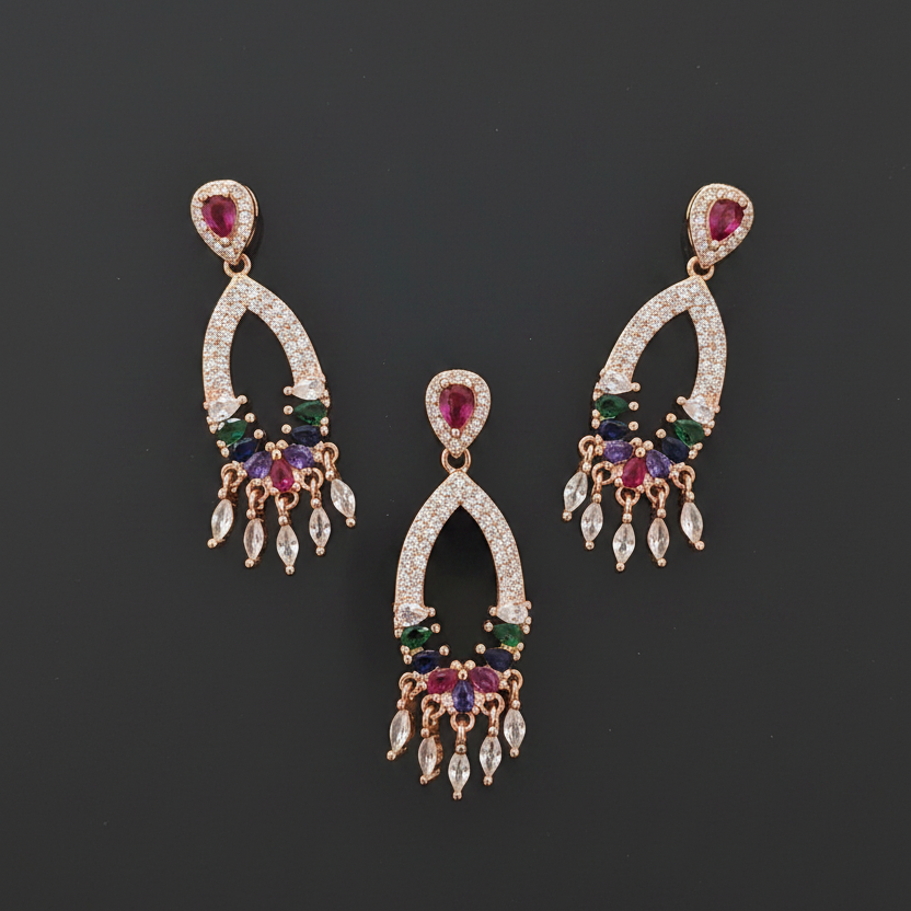 Gold earrings with multicolored gemstones held between fingers against a red fabric background