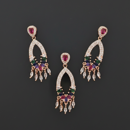 Gold earrings with multicolored gemstones held between fingers against a red fabric background