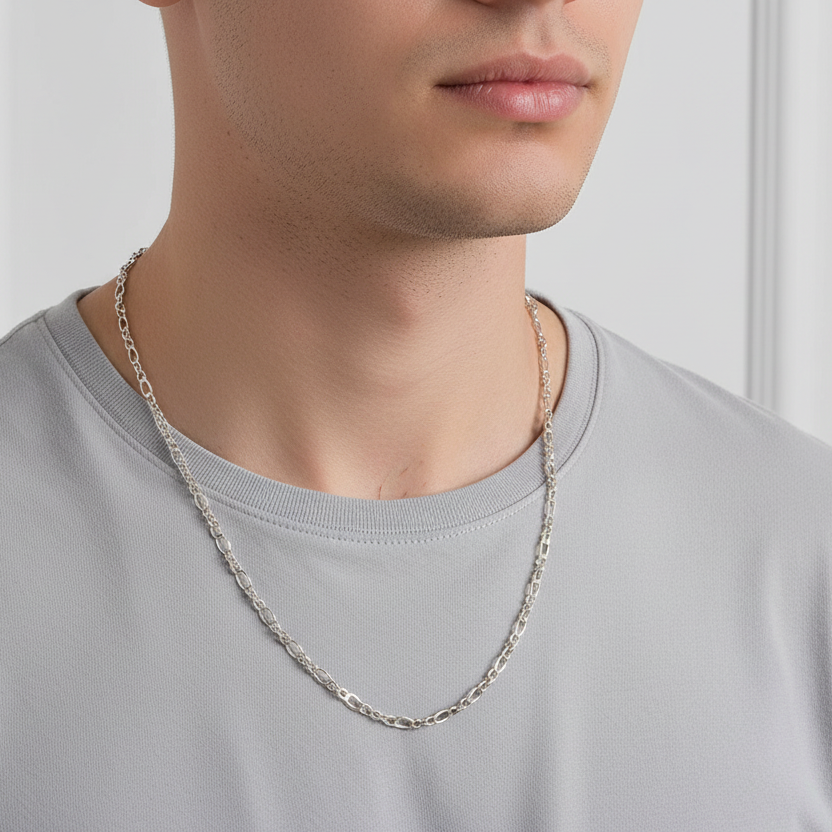 Person wearing a silver chain necklace against a neutral background