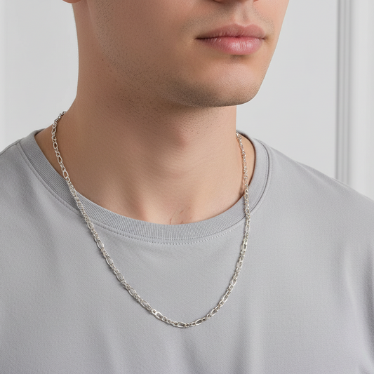 Person wearing a silver chain necklace against a neutral background