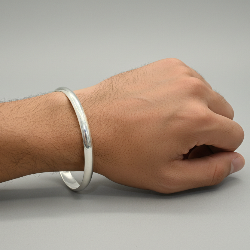 Hand wearing a silver bracelet on a gray background