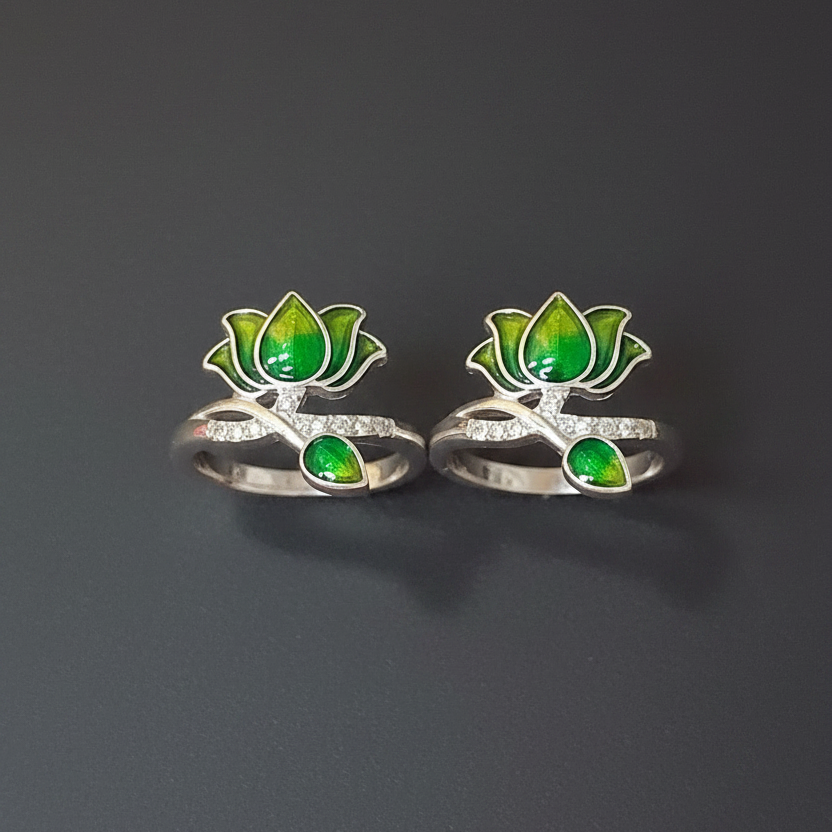 Two silver rings with green gemstones on a finger against a pink background