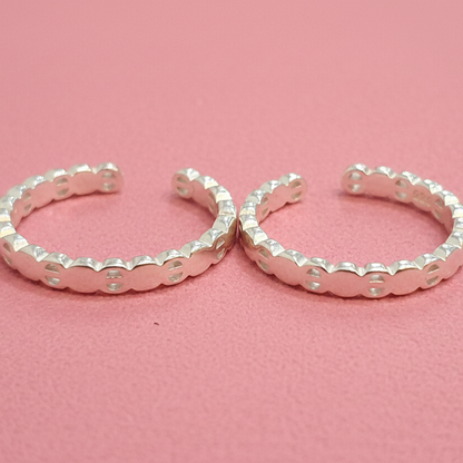 Pair of silver hoop earrings on a black stand with a red background