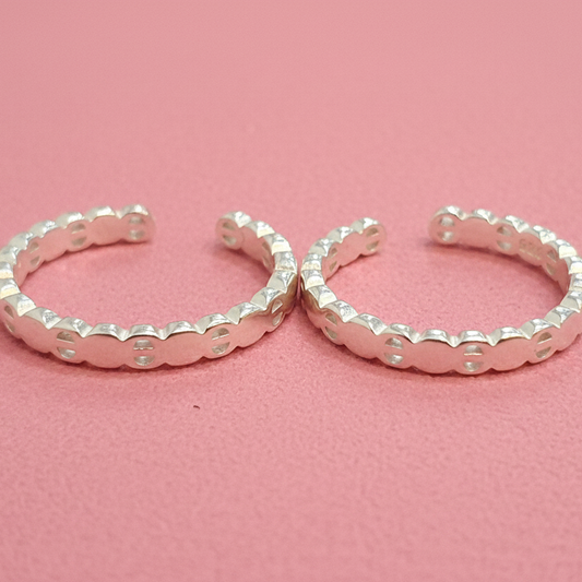 Pair of silver hoop earrings on a black stand with a red background