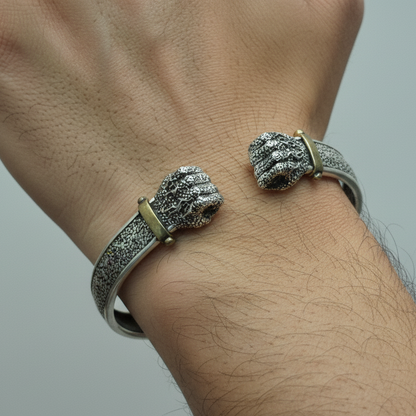 Silver bracelet with intricate design on a wrist against a neutral background