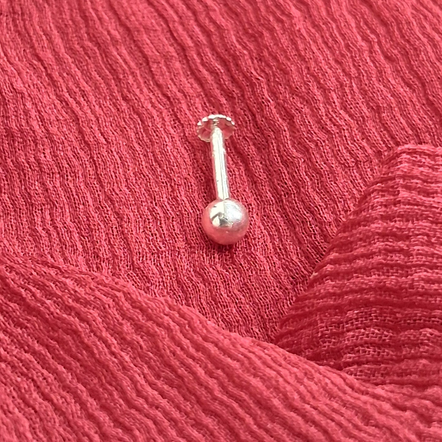 Silver barbell on red textured fabric
