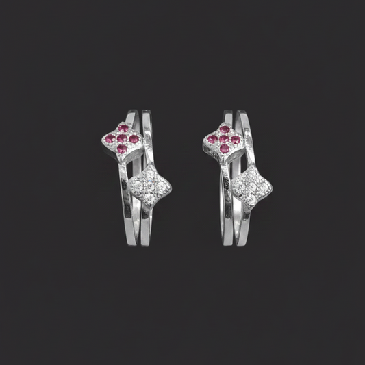 Three gold rings with gemstones on a finger against a pink background