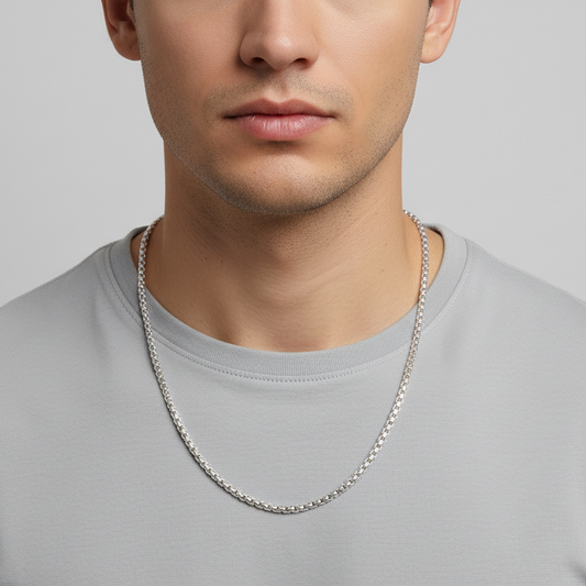 Man wearing a silver chain necklace against a plain background