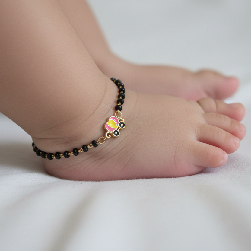 Baby's foot wearing a black beaded anklet on a white background