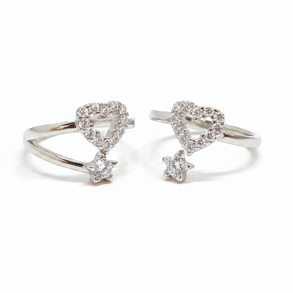 Two diamond-studded heart-shaped rings on a black stand with a pink background