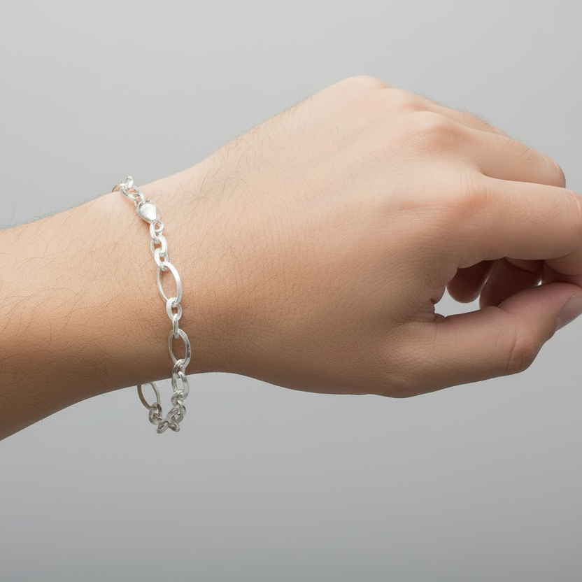 Silver chain bracelet on a wrist against a gray background