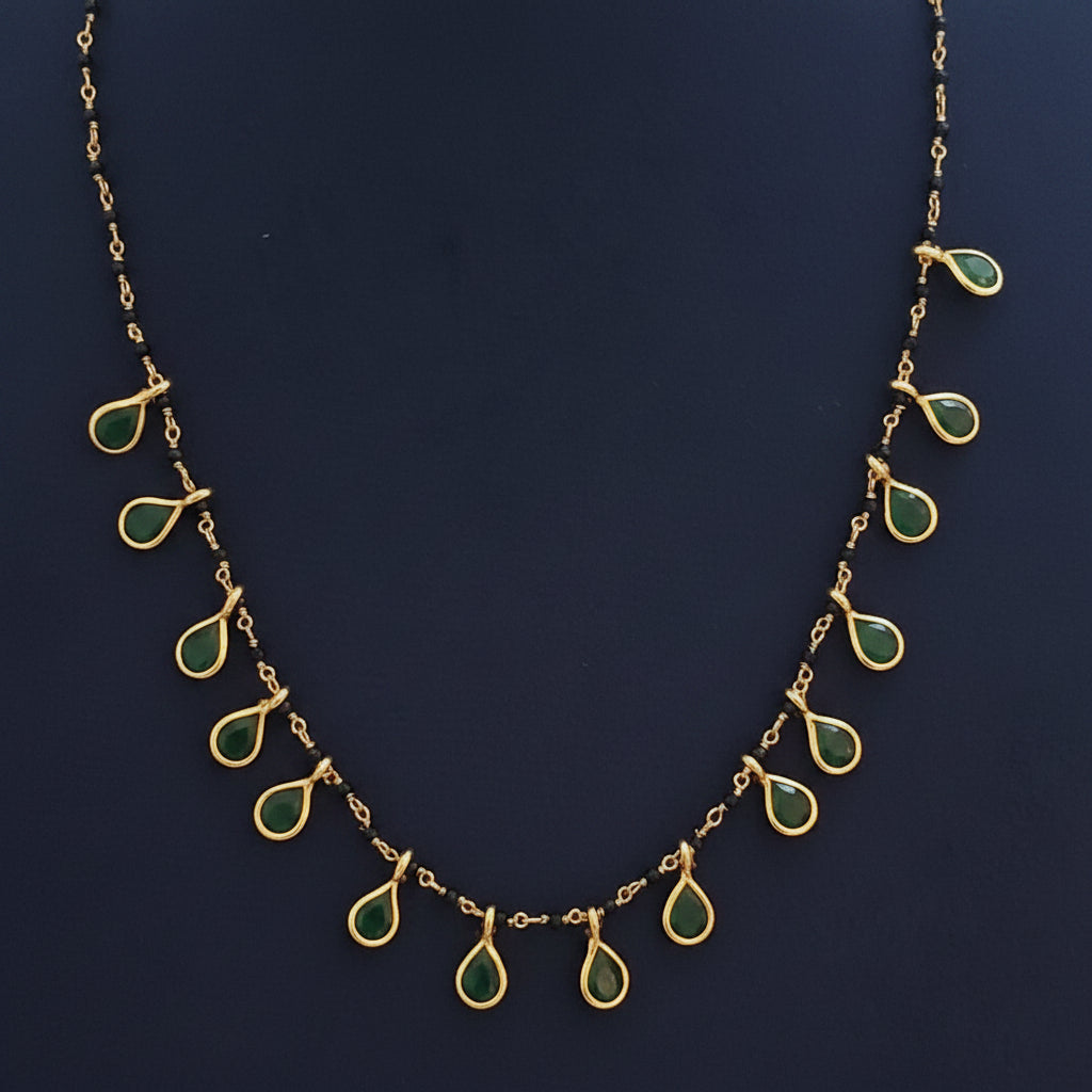 Gold necklace with green gemstones on a red fabric background