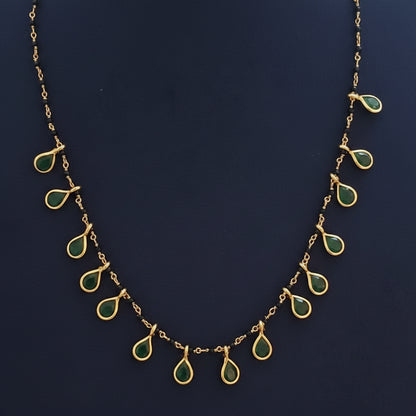 Gold necklace with green gemstones on a red fabric background