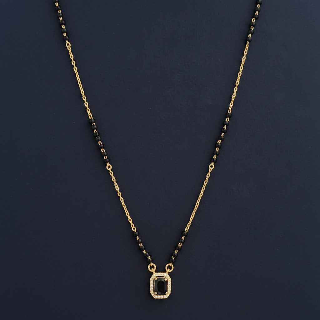 Necklace with black beads and gold chain on a red cushion