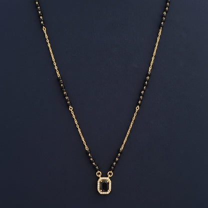 Necklace with black beads and gold chain on a red cushion