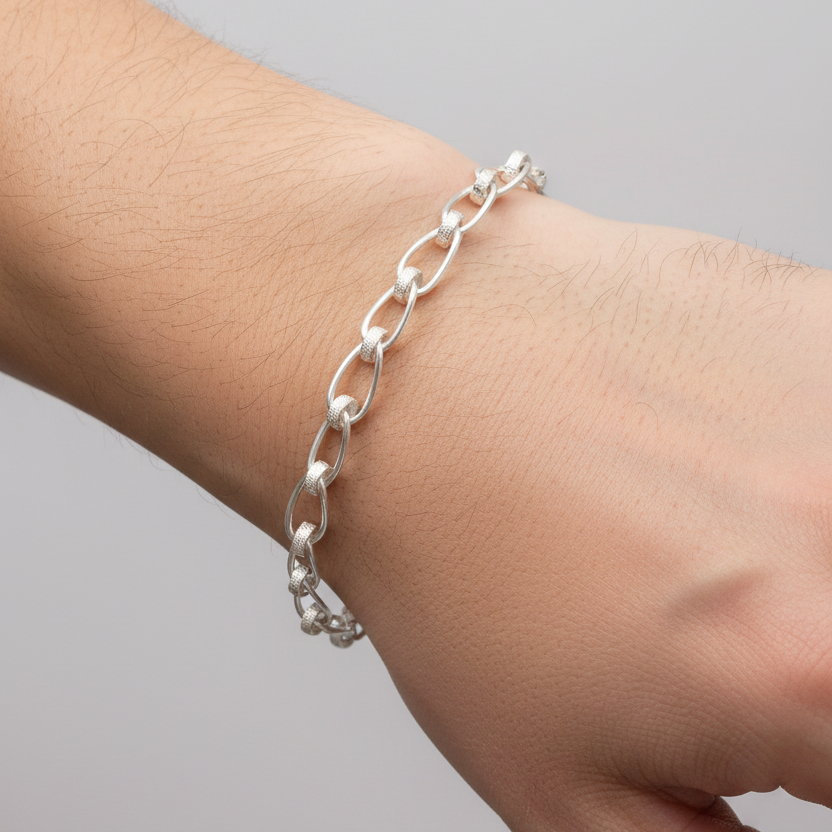 Silver chain bracelet on a wrist against a gray background