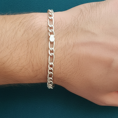 Silver chain bracelet on a wrist against a teal background