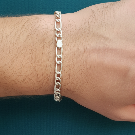 Silver chain bracelet on a wrist against a teal background