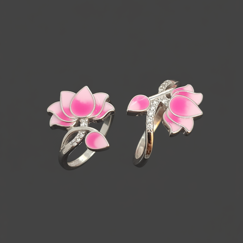 Two pink lotus flower rings with silver leaves on a finger against a dark background.