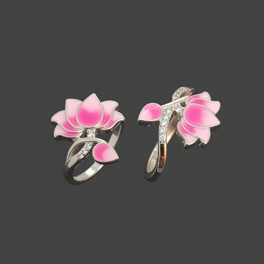 Two pink lotus flower rings with silver leaves on a finger against a dark background.