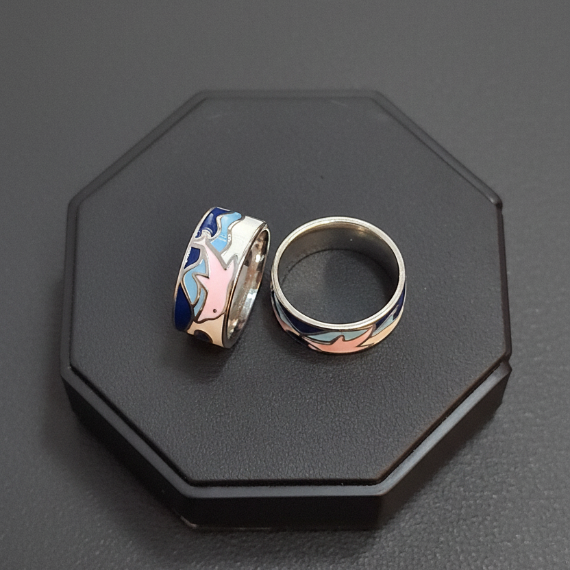 Three colorful dolphin-themed rings on a finger against a pink background