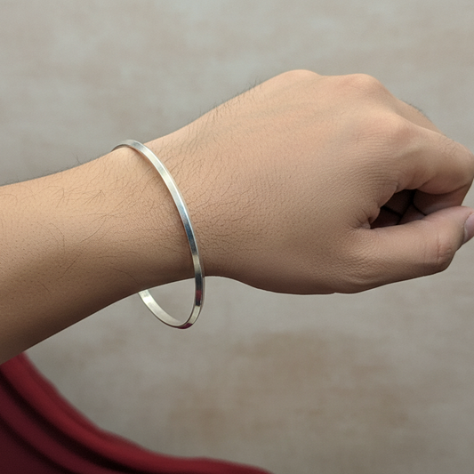 Silver bracelet on a wrist with a neutral background