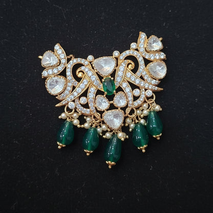 Jewelry piece with green stones and gold accents on a red background
