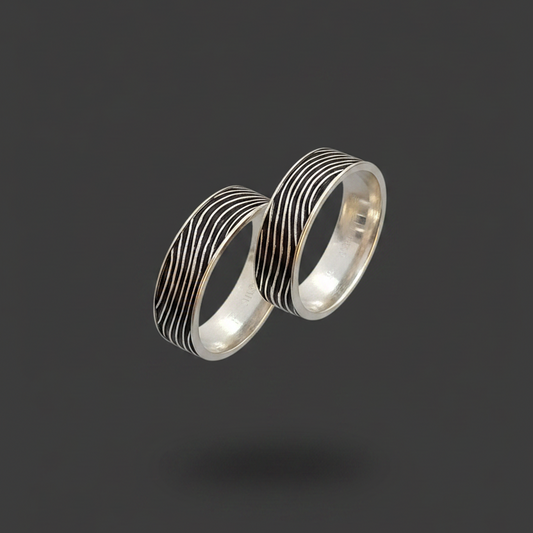 Two silver rings on a finger with a pink background