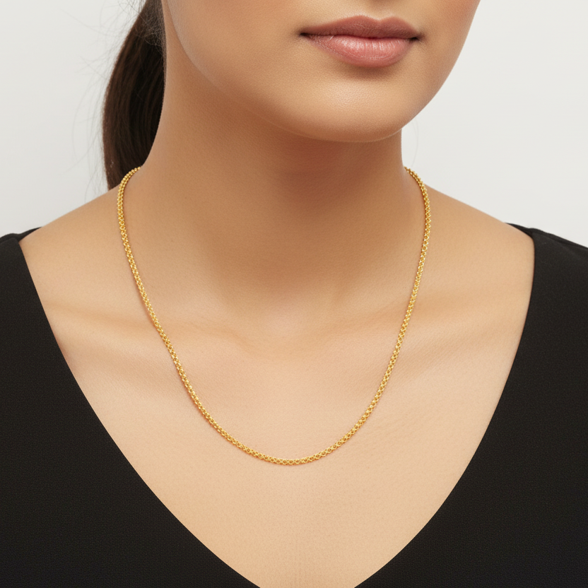 Gold necklace worn by a model on a plain background