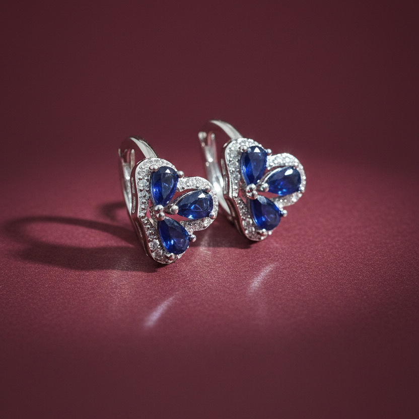 Two rings with blue gemstones on a hand against a pink background