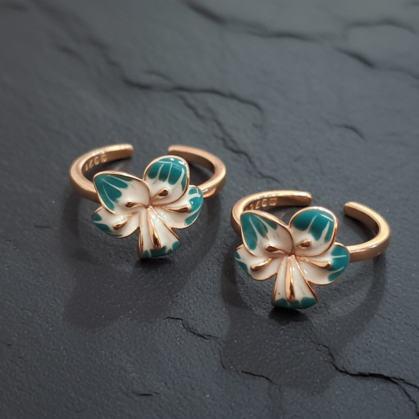 Butterfly-shaped gold and green rings on a dark stand with a pink background