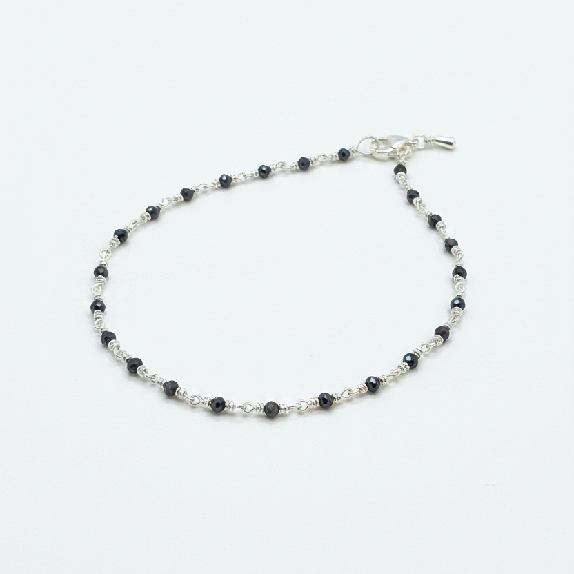 Silver beaded bracelet on a person's wrist with a red fabric background