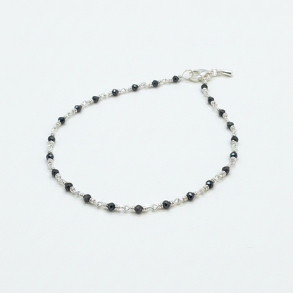 Silver beaded bracelet on a person's wrist with a red fabric background