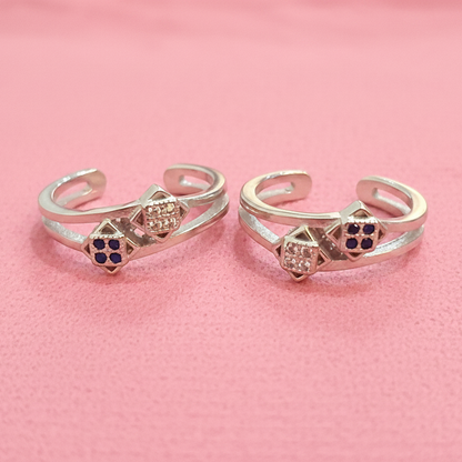 Two gold rings with gemstones on a black stand against a pink background