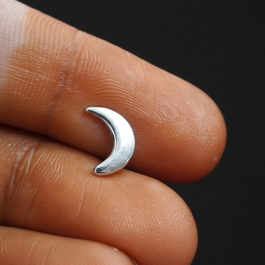 Silver crescent moon ring on a person's finger with a red fabric background