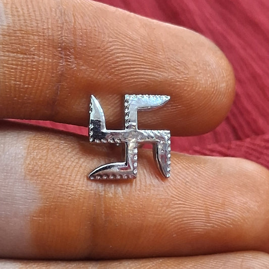 Silver swastika ring on a finger against a red fabric background