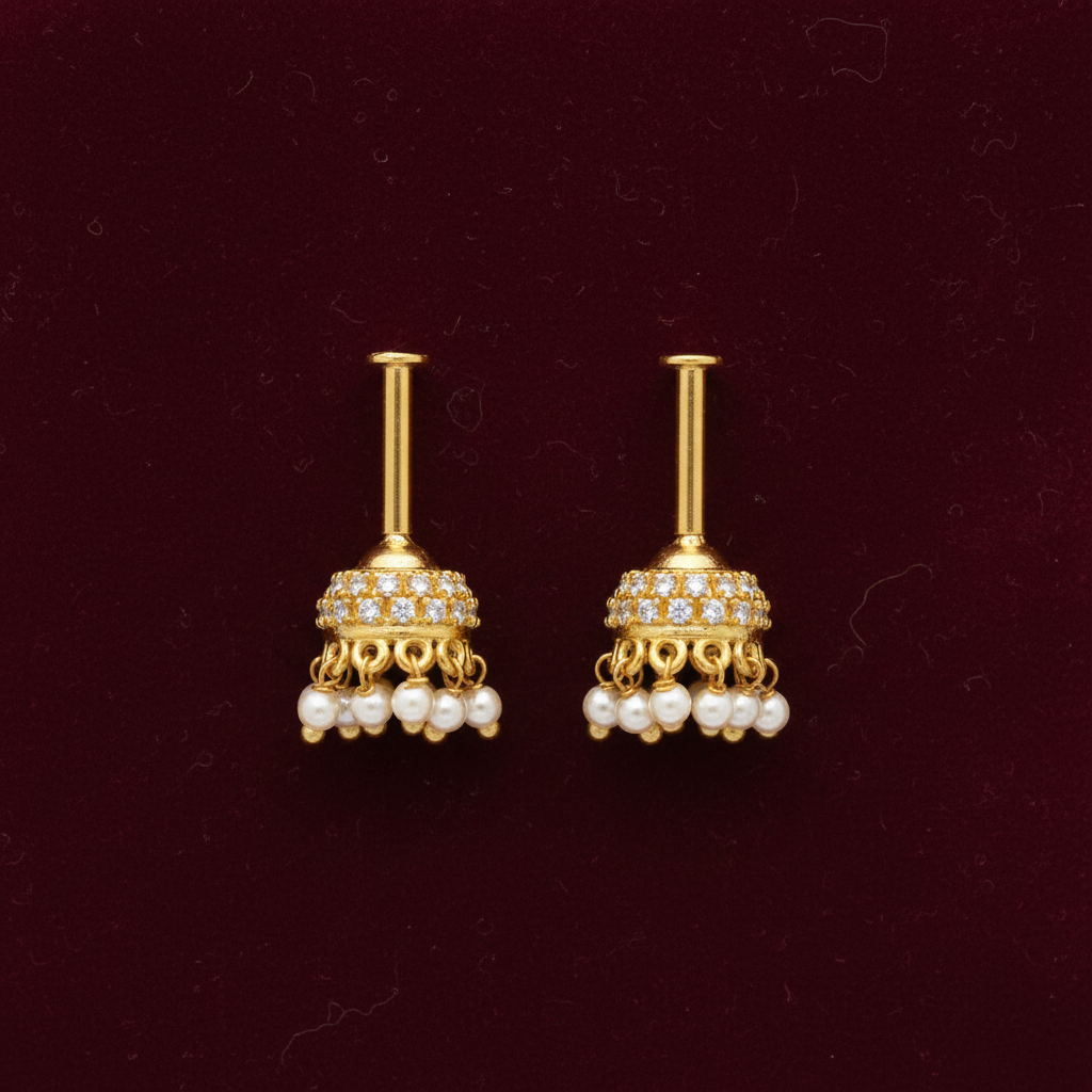 Pair of gold earrings with pearl accents on a maroon background