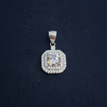 Silver pendant with a clear gemstone on a red fabric background, measured by a ruler.