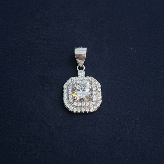 Silver pendant with a clear gemstone on a red fabric background, measured by a ruler.