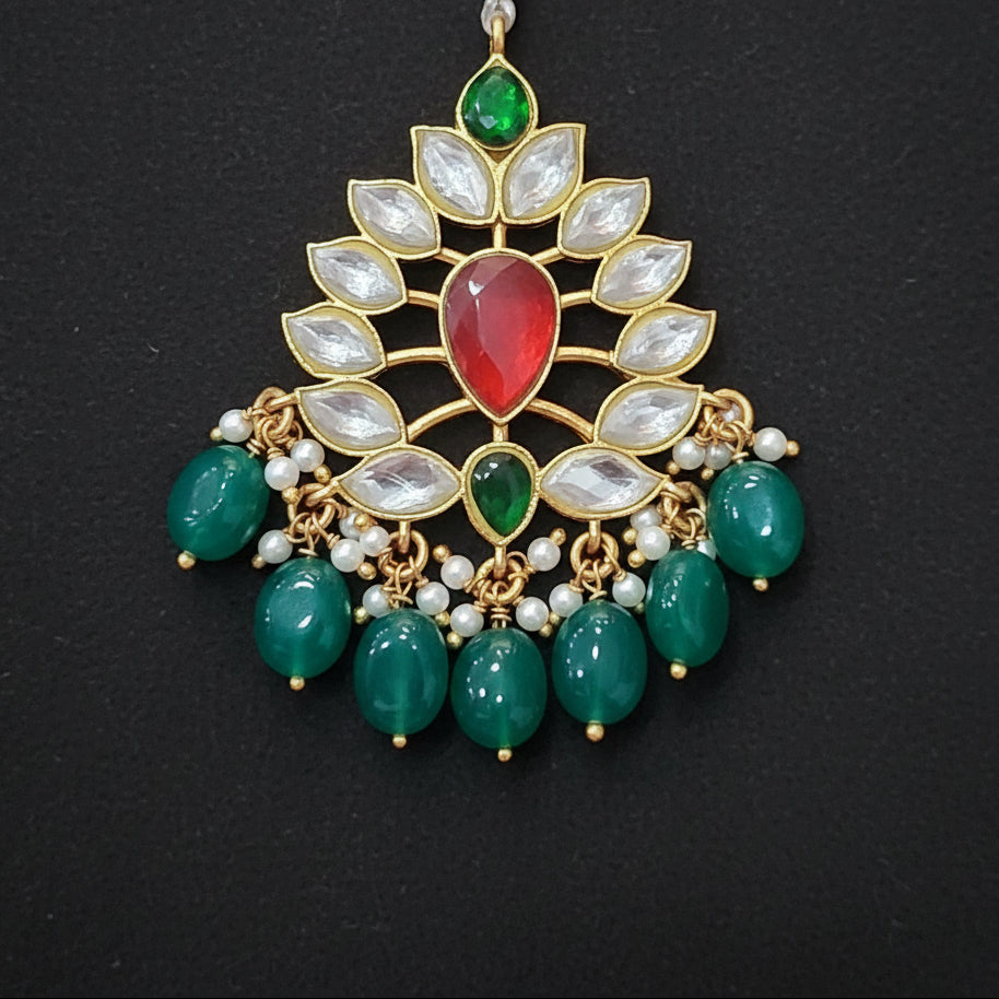 Decorative pendant with green and red stones on a maroon background