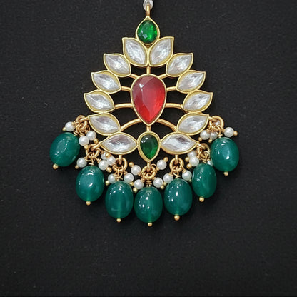 Decorative pendant with green and red stones on a maroon background
