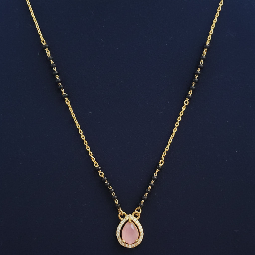 Gold necklace with pink pendant on a red fabric background