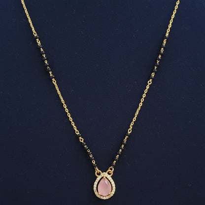 Gold necklace with pink pendant on a red fabric background